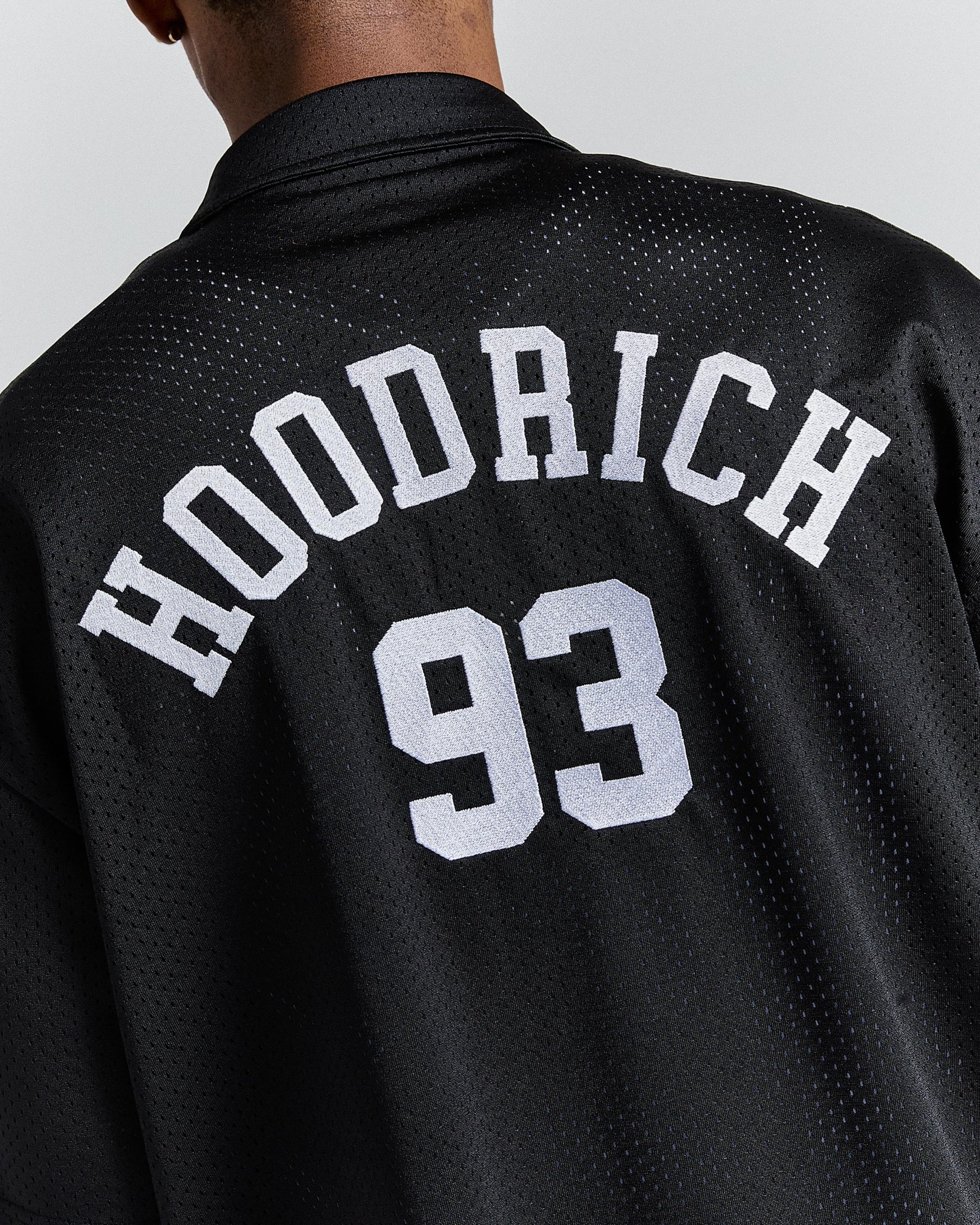 Black jacket with 'Hoodrich 93' text on the back against a light gray background