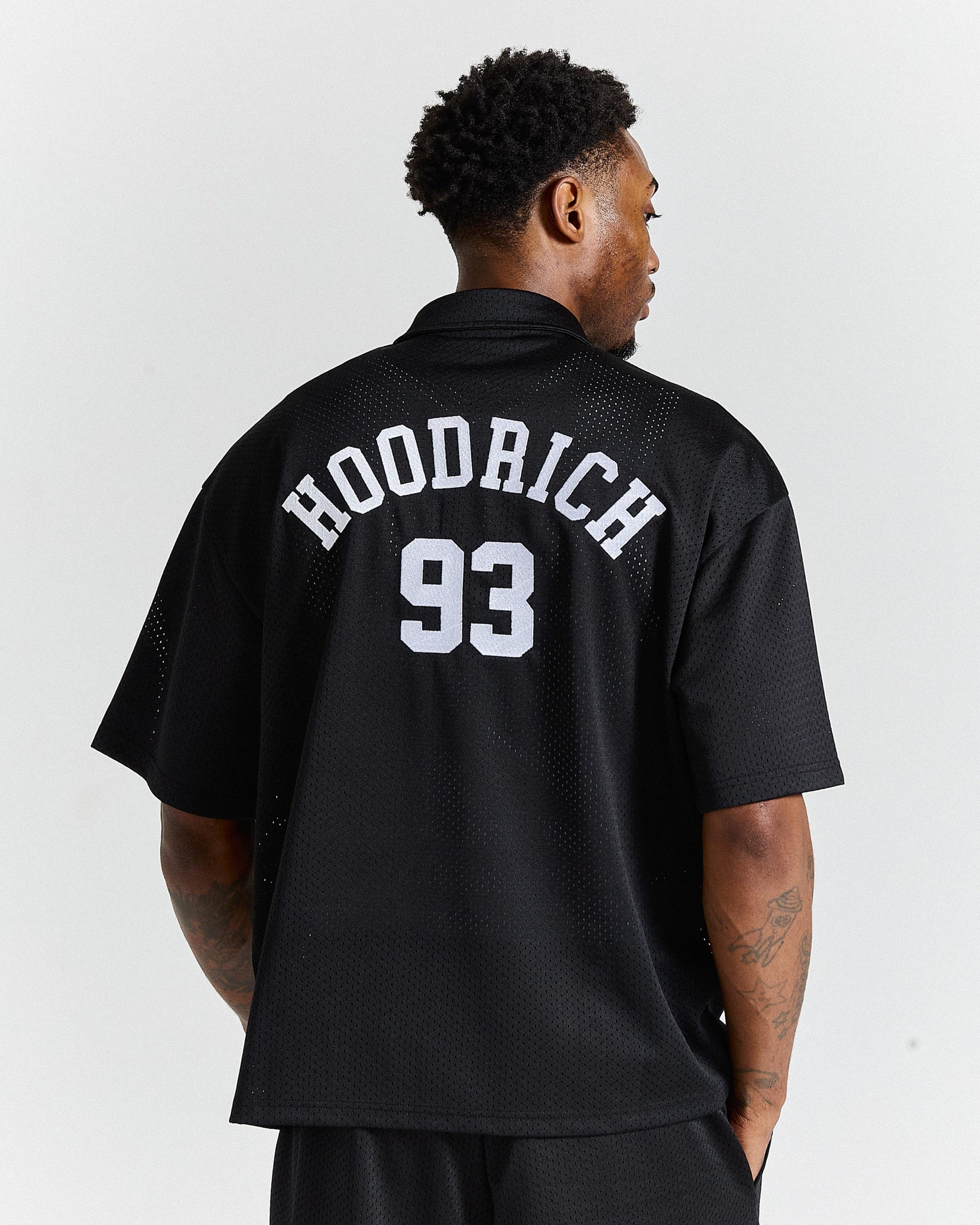 Person wearing a black 'Hoodrich 93' jersey on a white background