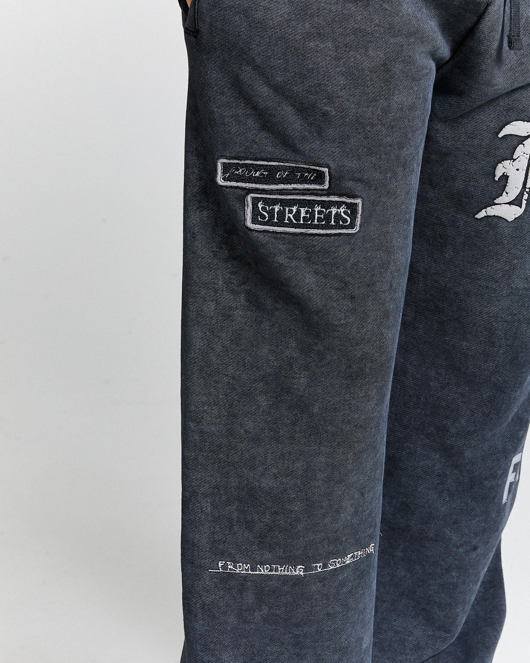 Dark gray sweatpants with embroidered text on a white background