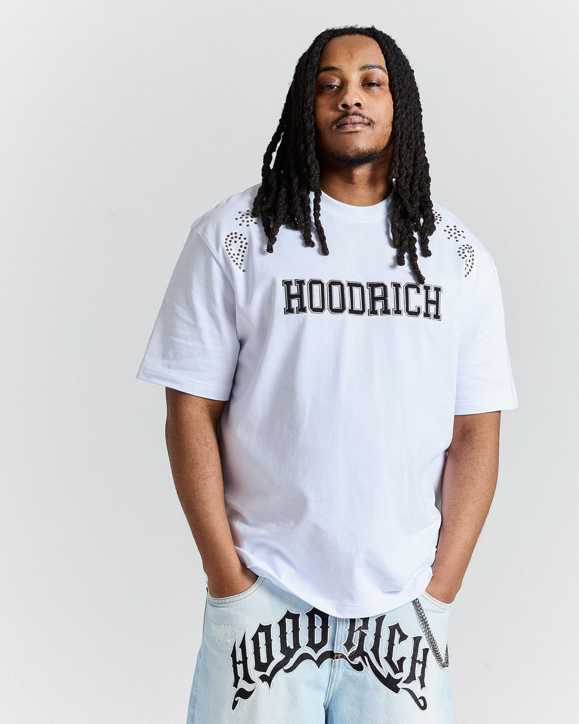 Person wearing a white 'Hoodrich' t-shirt and light blue pants with the brand name.